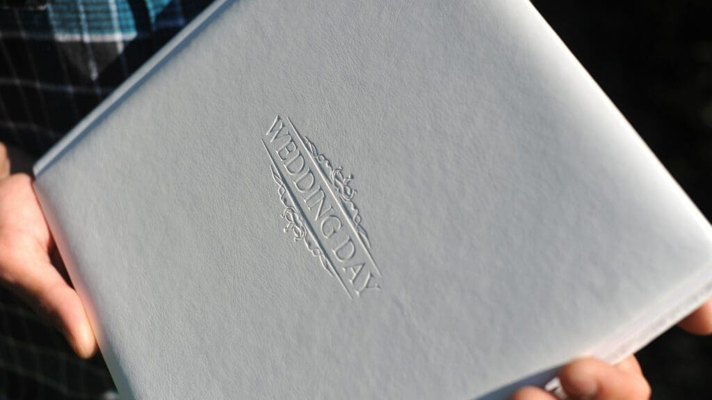 Hand holding a wedding day album cover.