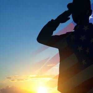 Silhouette saluting against American flag backdrop.