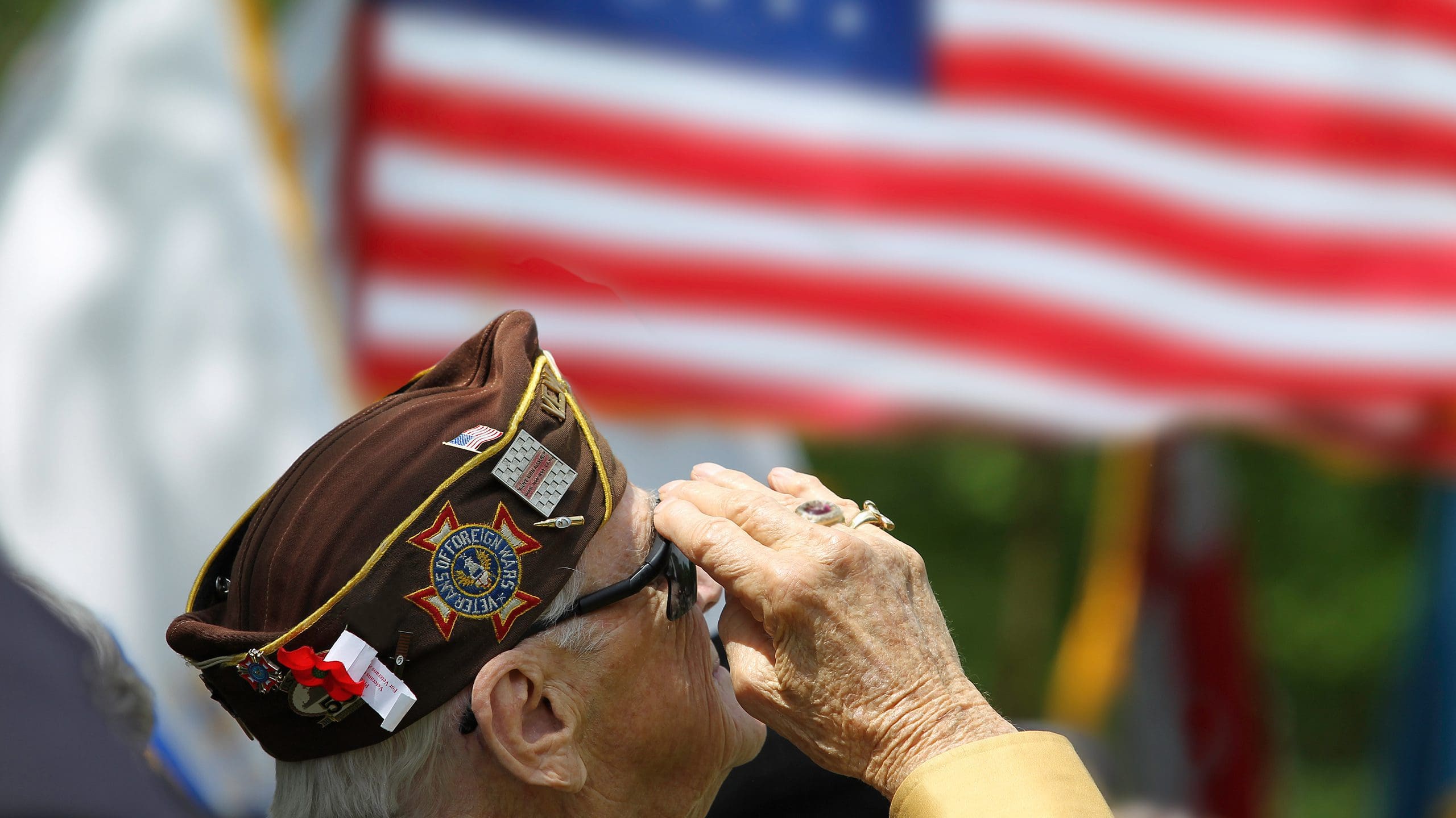GettyImages-528462035 Veteran saluting in front of American flag.