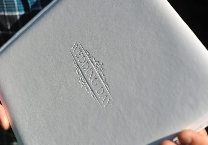 Hand holding a wedding day album cover.