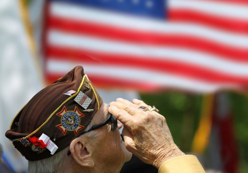 Veteran saluting in front of American flag.